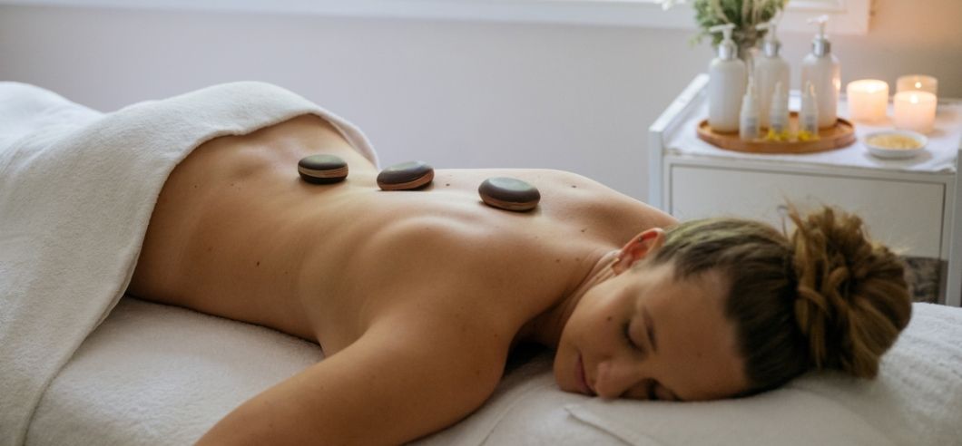 A lady lying on a massage table at Bells of Killcare, with hot stones on her back.