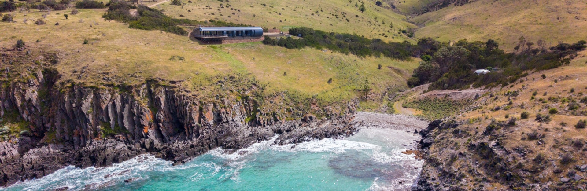 A photo of Naiko Retreat in The Fleurieu Peninsula, perched on a green hill overlooking the turquoise water
