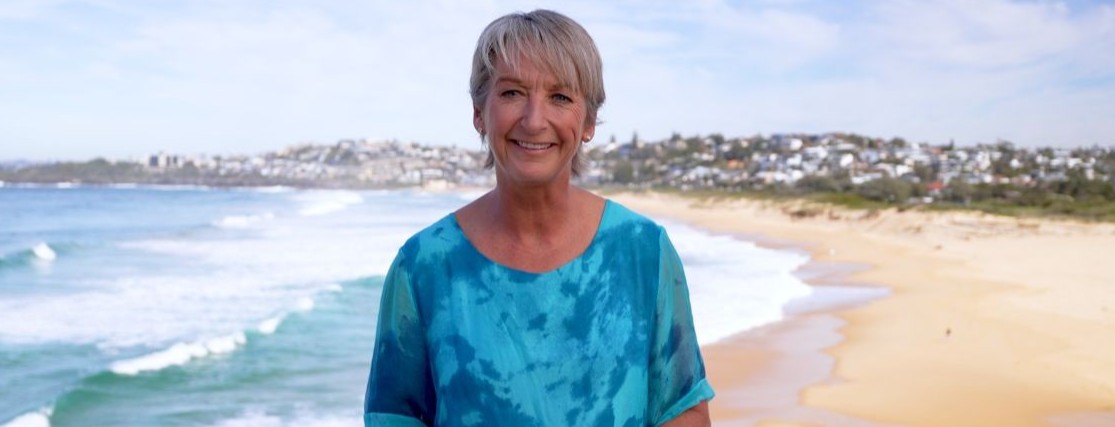 Layne Beachley wearing a blue top with an australian beach in the background
