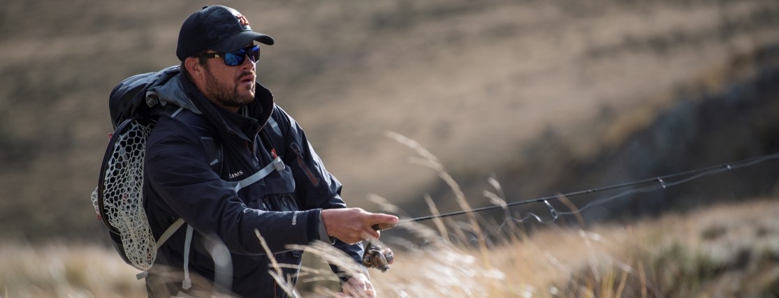 a man fly fishing in the snowy mountains in summer