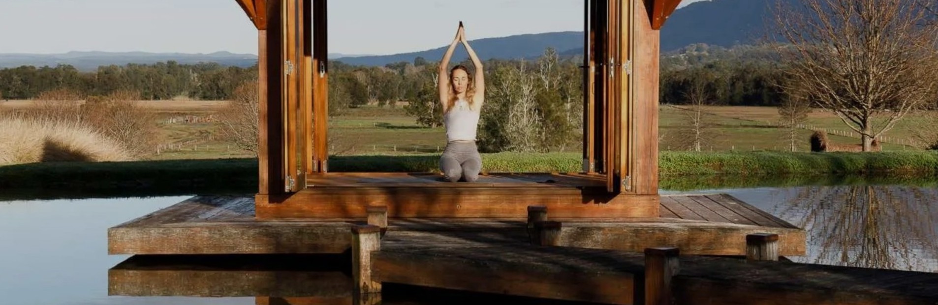 A lady doing a yoga pose in a meditation hut on a dam at a Farm near Berry in NSW