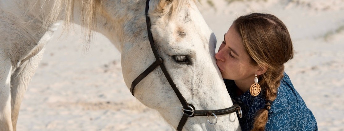 a woman kissing a white horse on its nose