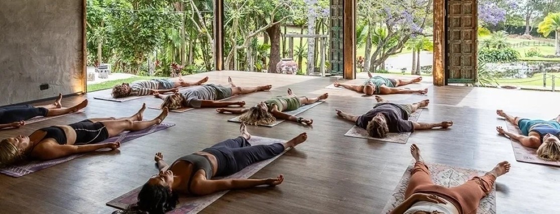 a group of people lying on yoga mats in an open-air yoga studio