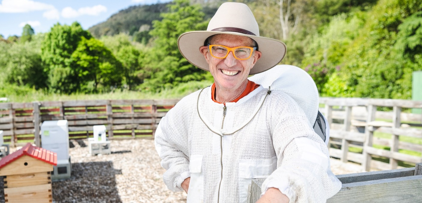 A beekeeper wearing a suit near a beehive