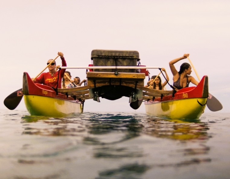 A group of people paddling in a traditional Hawaiian double hull canoe