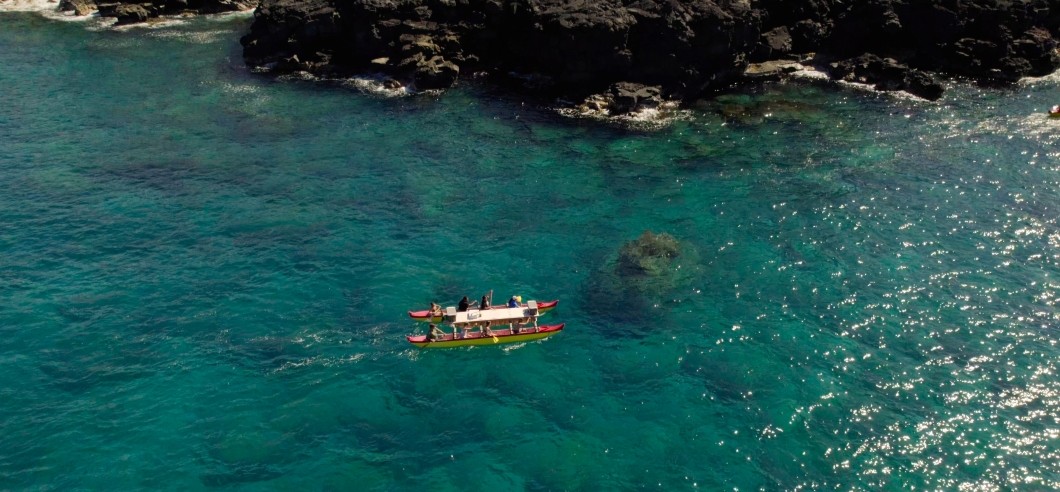A group of people paddling in a traditional Hawaiian double hull canoe