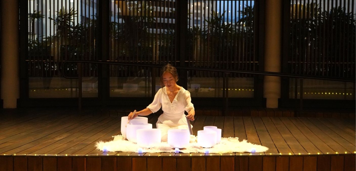 a japanese woman hosting a sound healing at night with crystal singing bowls