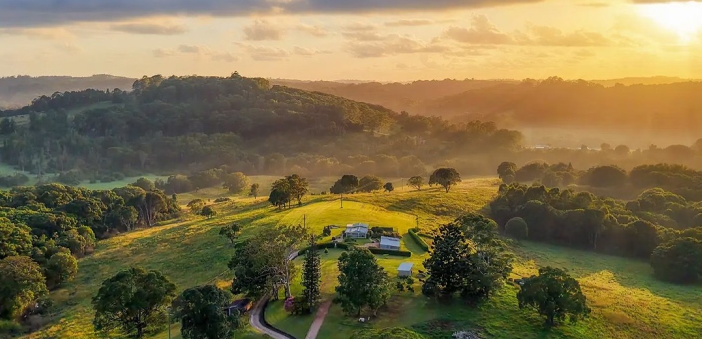 An aerial view of a lush green farm in Byron bay at sunset