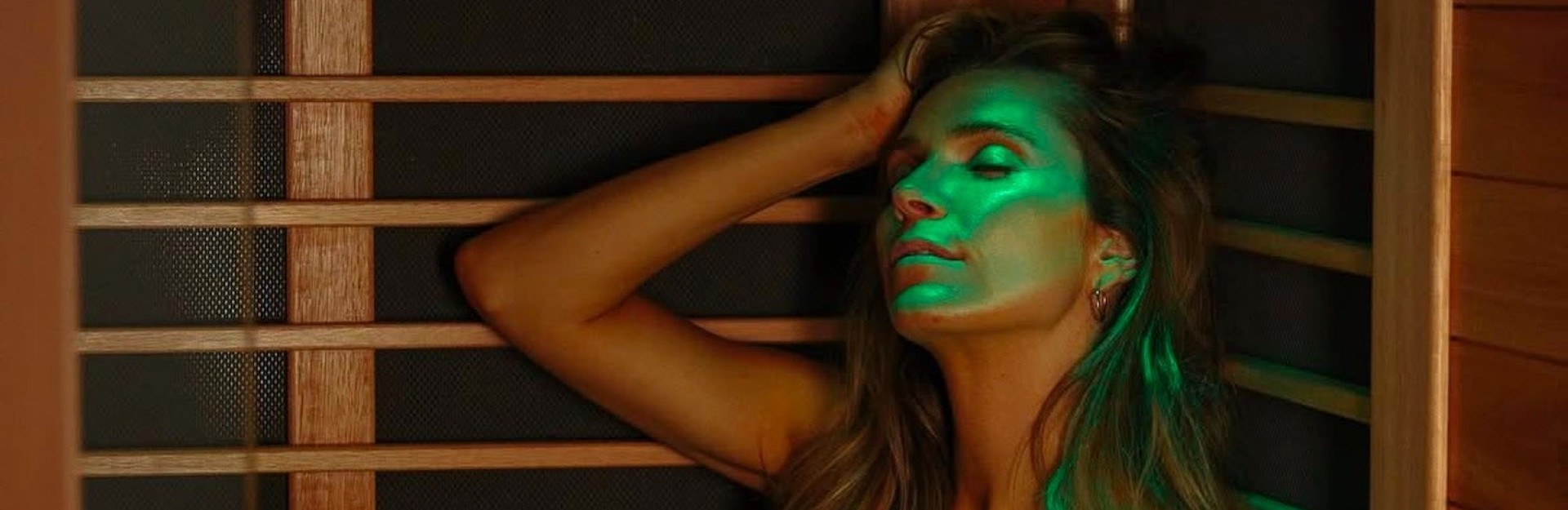 A lady relaxing in a sauna with green light on her face