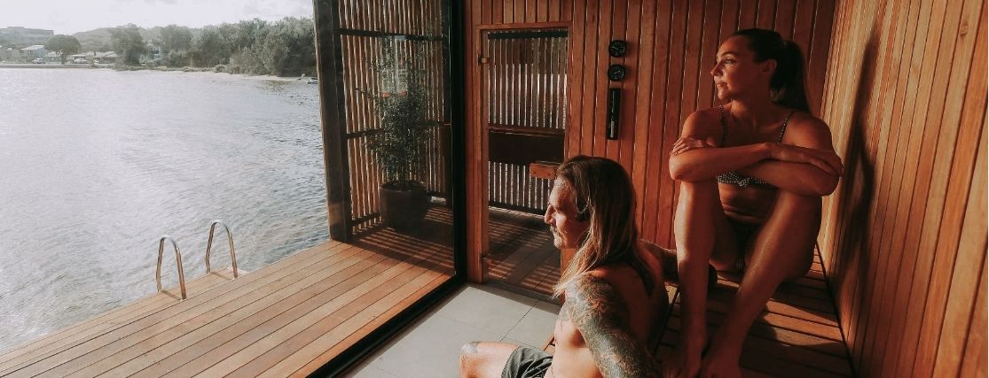 a couple in a floating sauna looking to the water