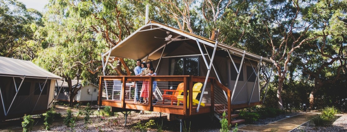 a family on the balcony of a glamping tent in the australian bush