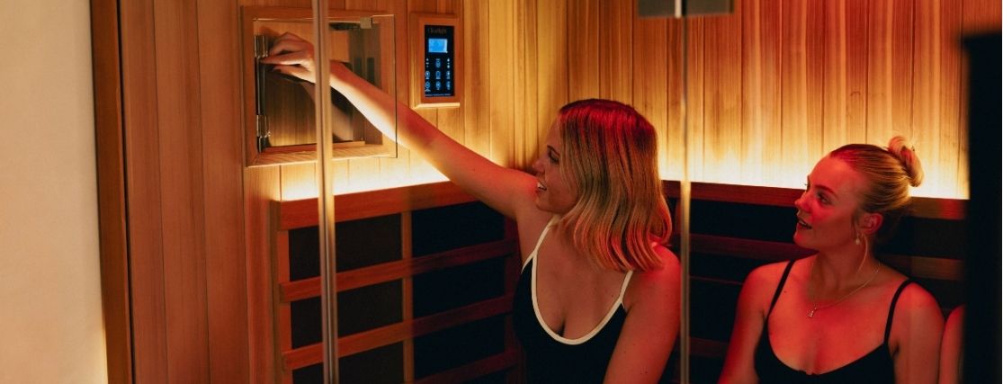 2 ladies in a sauna, adjusting the temperature