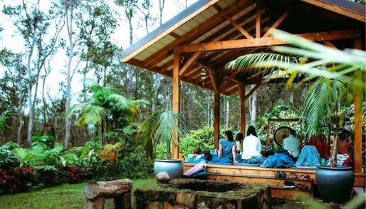 a group of people resting in a cabana surrounded by a lake in a cloud forest