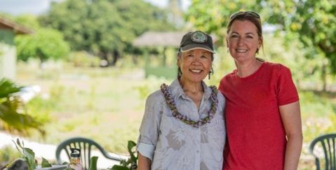 Phyllis from Forest Bathing Hawaii and a friend standing in front of a table with flowers