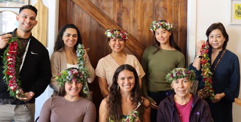 a group photo of people after a Lei-making class in Hawaii, wearing their lei's on their heads