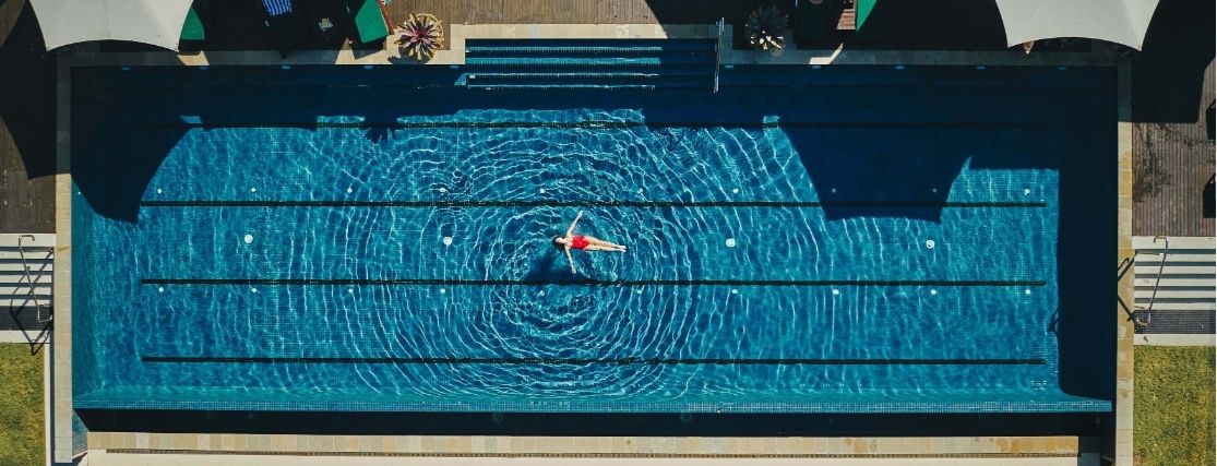 an aerial view of the pool at crystalbrook byron resort, with a lady in a red swimsuit floating in the middle