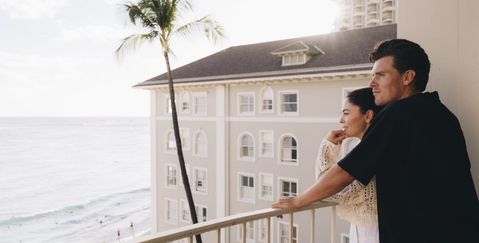 a couple standing on the balcony of their apartment at the Moana Surfrider hotel in Oahu