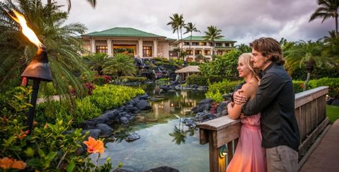 a couple standing on a bridge over the pools of the Grand Hyatt Kauai