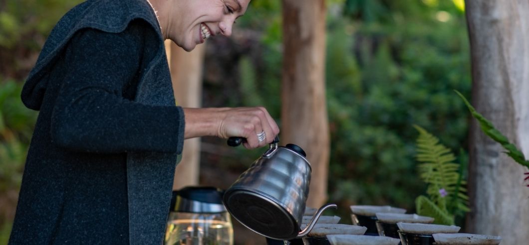 A lady pouring freshly brewed coffee into a french press