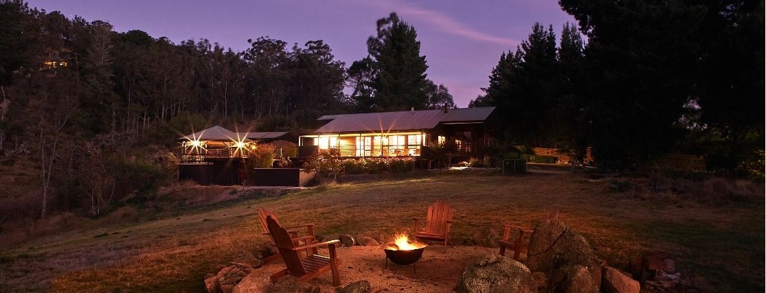 The view of The Lodge at Mt Kanimbla Retreats at dusk with a firepit in the foreground