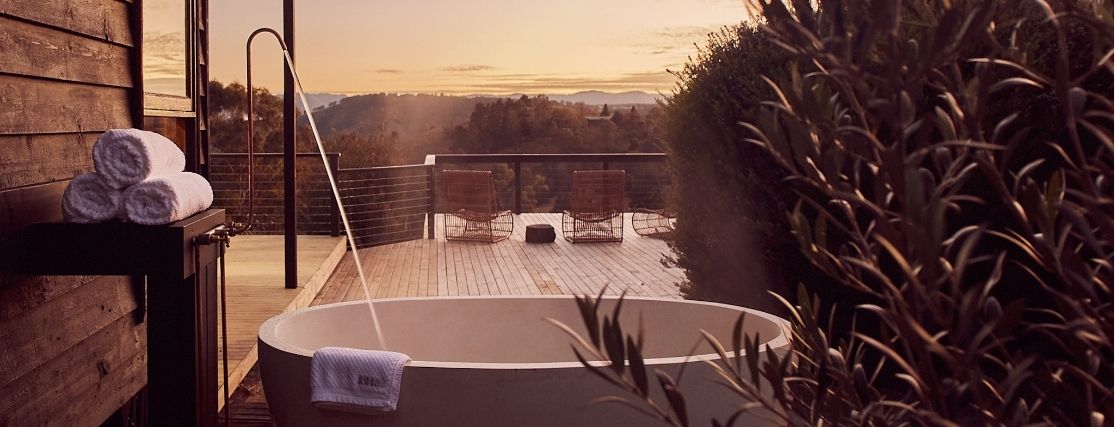 an outdoor bath being filled with views to the blue mountains at dusk