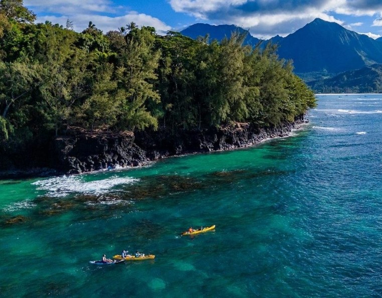 a group of kayakers paddling along the Kauai Coast in Hawaii