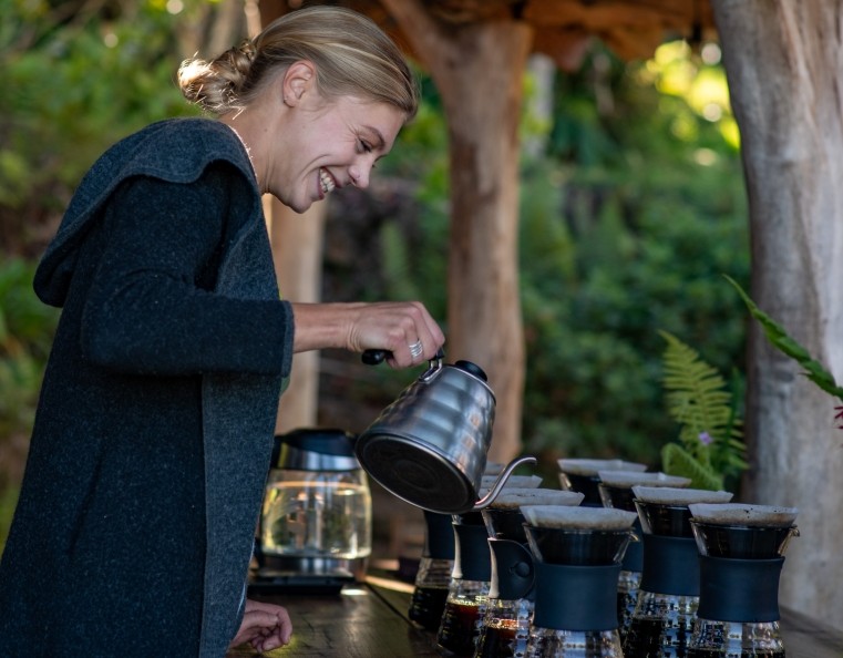 A lady pouring freshly brewed coffee into a french press