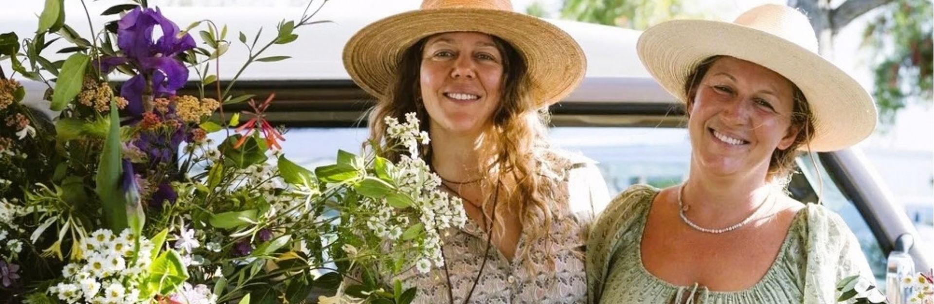 two women wearing sun hats and selling fresh flowers at a farmers market in Maui