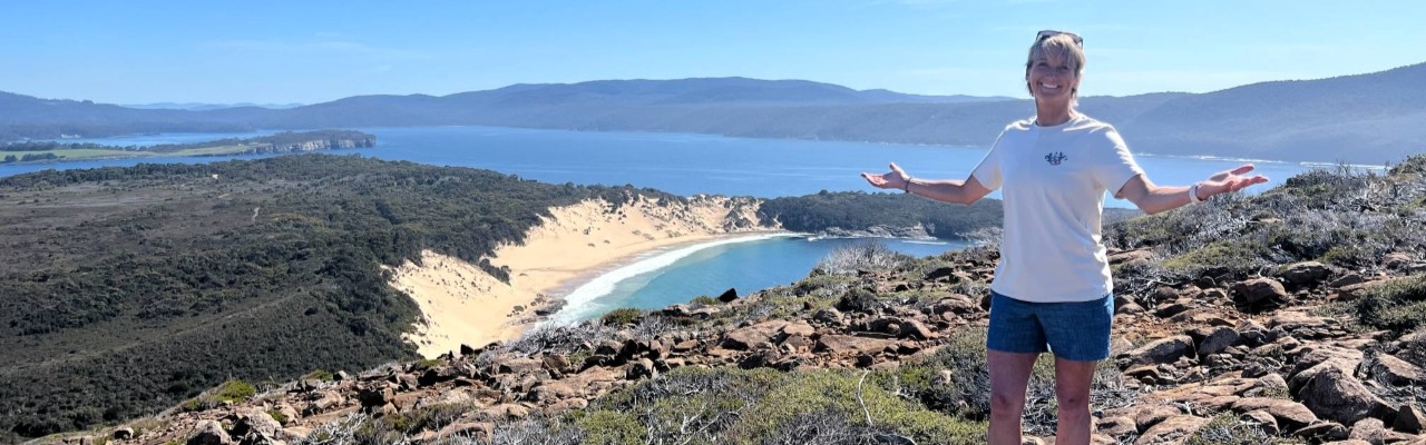 Layne Beachley standing on a hill in Tasmania overlooking the coast on a sunny day